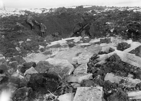 Image © IWM (Q 1684) – Officers inspecting chunks of ice broken up by shell fire on the battlefield at Beaumont Hamel, December 1916.